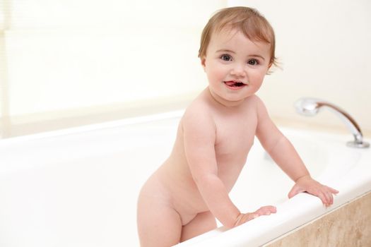 She wants to get out now. An adorable baby girl climbing out of the bath.