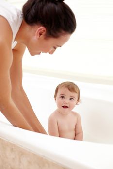 Her favorite time of day. A mother washing her adorable baby girl in the bath.