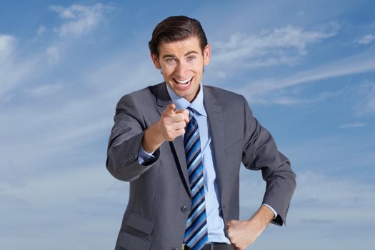 I want you. A young businessman pointing at you against a blue sky.