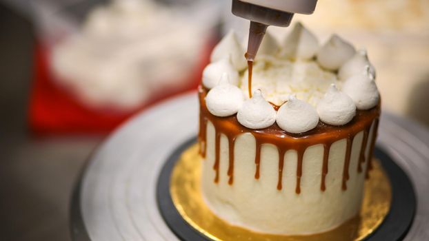 chef designer squeezing bottle with salty caramel filling topping frosted cake