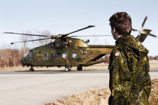 At the drop zone. A young soldier looking at an army helicopter.