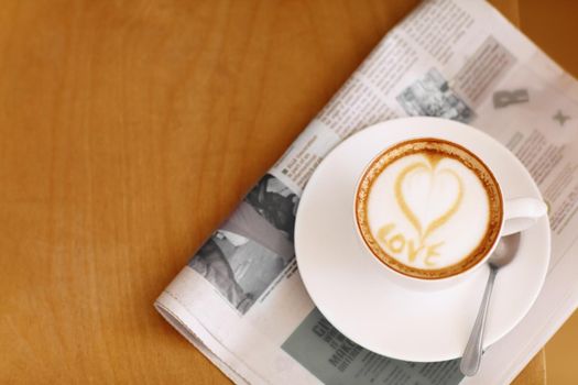 Made with love...High angle shot of a lovingly prepared cup of cappuccino sitting on a newspaper.