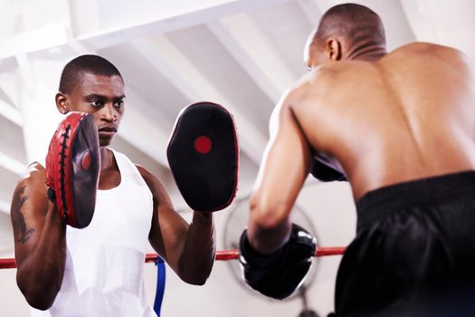 Give it your all. A boxer practicing with his sparring partner in the ring.