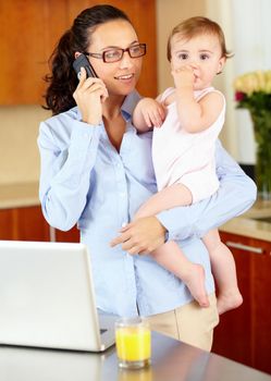 She makes balancing work and home look easy. a happy-looking single mom talking on the phone while cradling her baby.