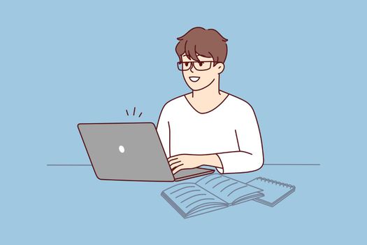 Smiling man sit at desk work on laptop