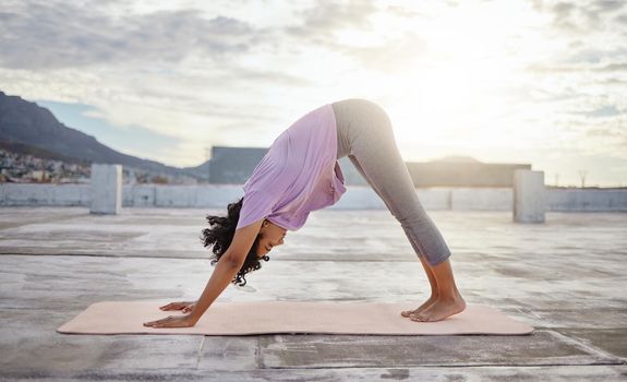 Yoga exercise, city rooftop and woman bending down for balance, wellness and health on an urban building in the morning. Fitness girl training and active during a healthy workout against overcast sky