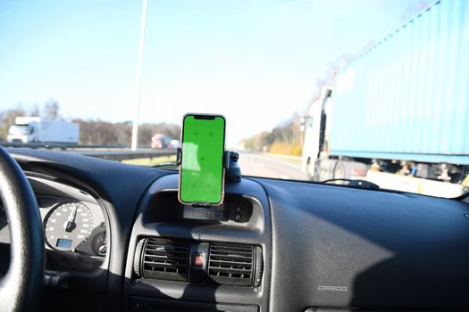 Smartphone with green screen in windshield holder in the car for navigation