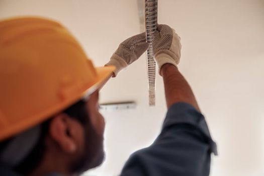 Close up of electrician worker in uniform is installing electric lamps light in kitchen