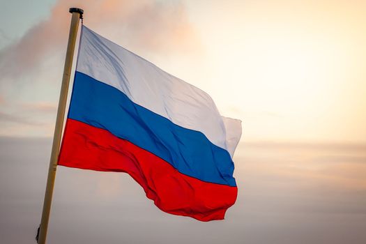 Flag of Russia waving in the wind at golden sunset, Moscow, Russia