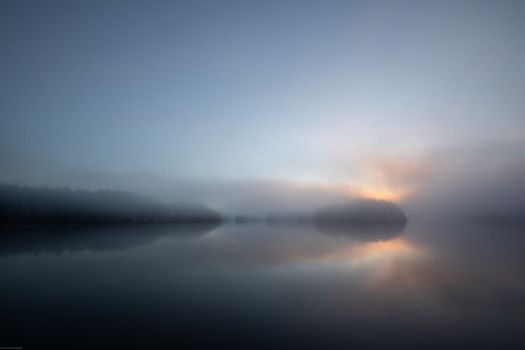 Morning mist with sun peeking through clouds and reflection in the water, Blunden Harbour, British Columbia