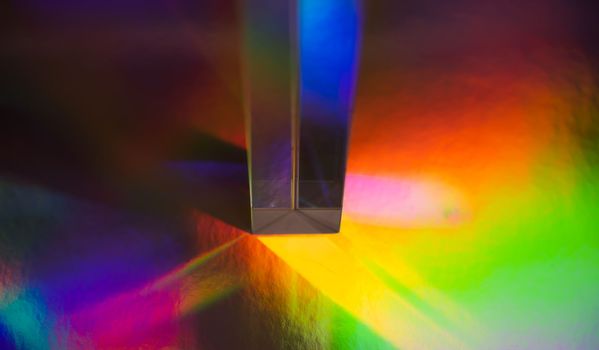 Glass prism on bright rainbow colors abstract background. Colorful polygonal multicolor banner.