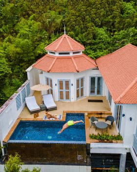couple in tropical pool villa during vacation, drone view at pool bungalow in rainforest