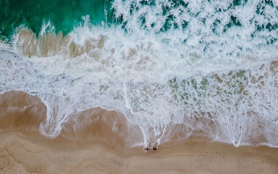 Top view at a tropical beach with waves and blue ocean Drone aerial view at Freedom beach in Phuket
