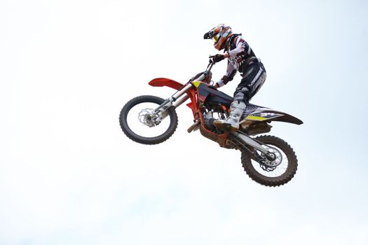 Thats some serious air. Low angle profile view of a motocross rider in the air against a cloudy sky.