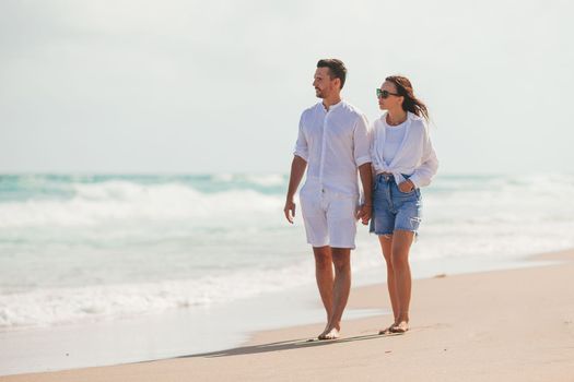 Young couple walking on the beach summer vacation. Happy man and woman look at the sea