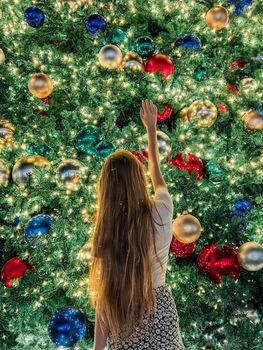 Young girl on the background of the Christmas tree in Miami. Beautiful Christmas Tree at the popular area at Xmas eve and lights