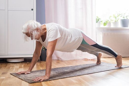 Middle aged woman in plank position keeps fit in her home