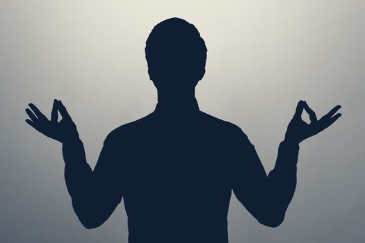 Unknown male person gray silhouette meditating at studio