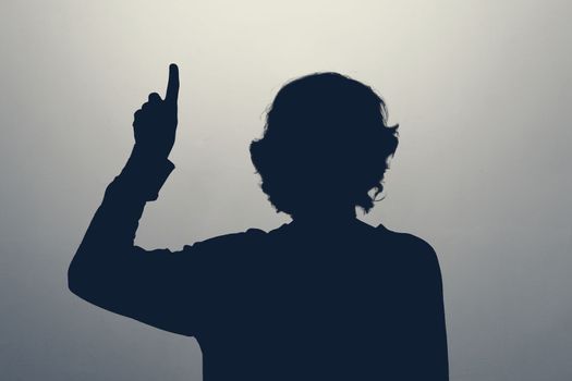 Unknown female person silhouette in studio pointing up