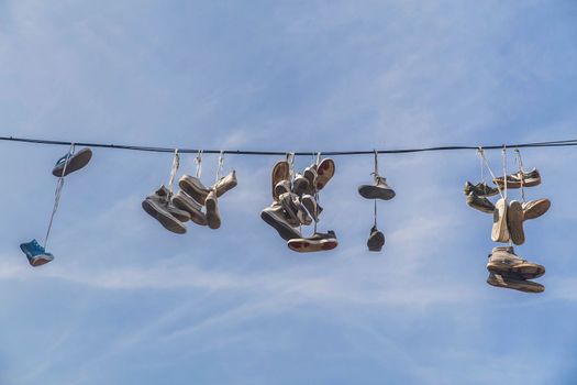 Old worn-out shoes hang from wires in slovenia