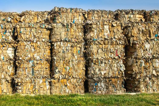 Large stacks waste paper for recycling on the grass outdoors