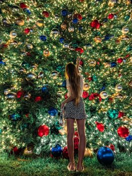 Young girl on the background of the Christmas tree in Miami. Beautiful Christmas Tree at the popular area at Xmas eve and lights