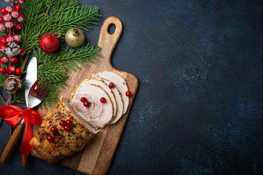 Christmas baked ham sliced with red berries and festive decorations