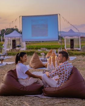 couple watching a movie outside during sunset,outdoor cinnema at night at the countryside of Thailand