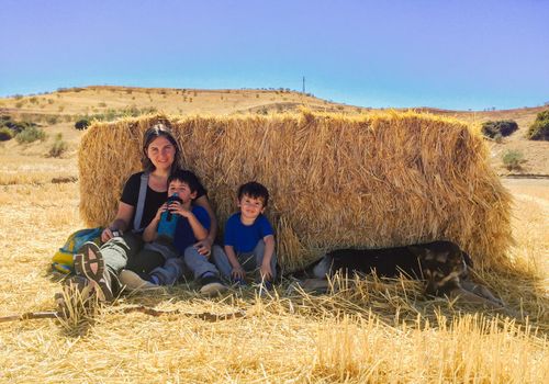 Mother with kids and dog behind straw sheltering from hot weather.