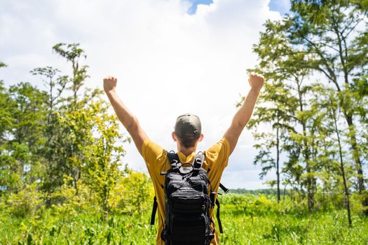 Male traveller with raised hands of happiness in the nature woods. Travel lifestyle freedom concept
