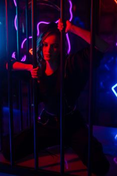Caucasian woman in a cage in a neon studio.
