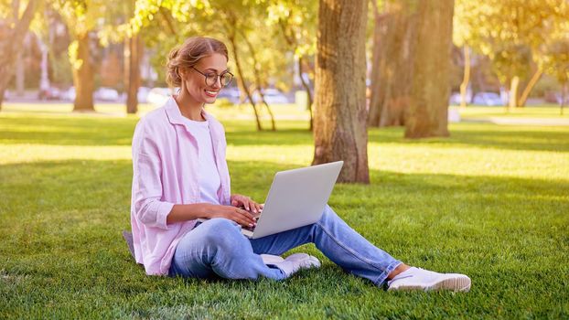 Businesswoman sitting grass summer park using laptop Business person working remote. Outdoor