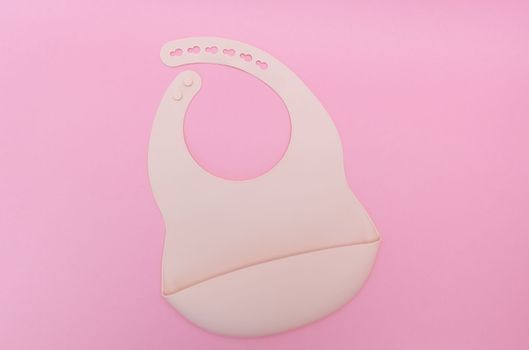 Silicone baby bib. Pastel pink color. top view, flat lay.