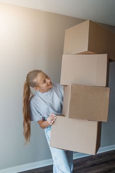 Happy girl moving in new house with cardboard boxes