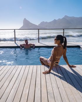 couple man and woman in front of Infinity pool looking out over the ocean of Cape Town South Africa
