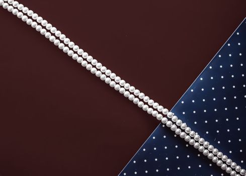 Pearl jewellery necklace and abstract blue polka dot background on chocolate backdrop