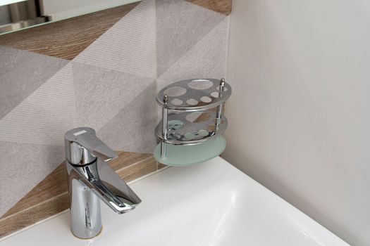 a special stand for toothbrushes in the bathroom interior. a sink and a modern mixer are visible. products for daily hygiene