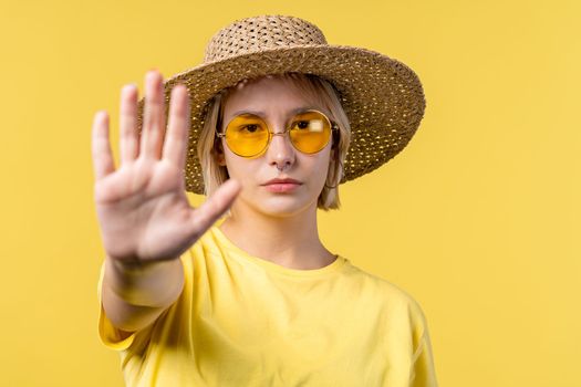 Uninterested woman disapproving with NO hand sign gesture. Denying, rejecting, disagree. Portrait of young lady on yellow background, timeout concept.