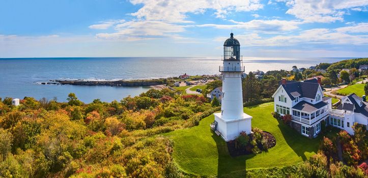 Lighthouse on hill with house overlooking stunning Maine coastline in fall