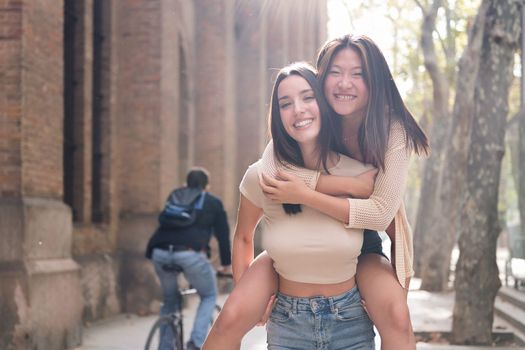 women in love smiling piggyback with her girlfriend
