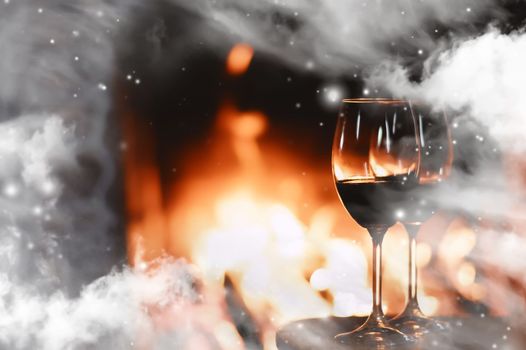 Winter atmosphere and Christmas holiday time, wine glasses in front of fireplace covered with snowy effect on window glass, holidays background