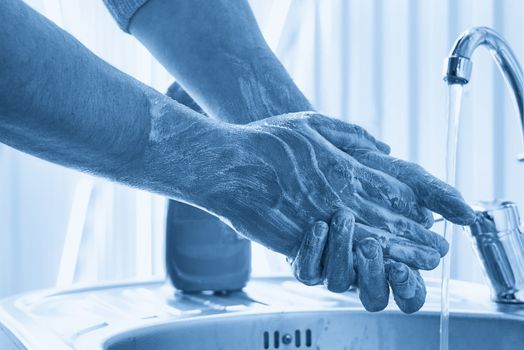 Mechanic washing dirty hands with soap after work