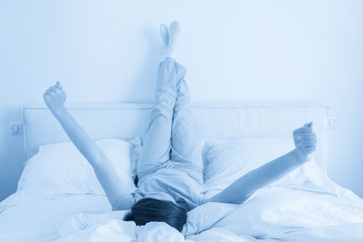Woman lying in bed with legs raised up against a wall