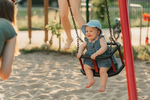 Toddler baby girl on a swing on the warm summer evening