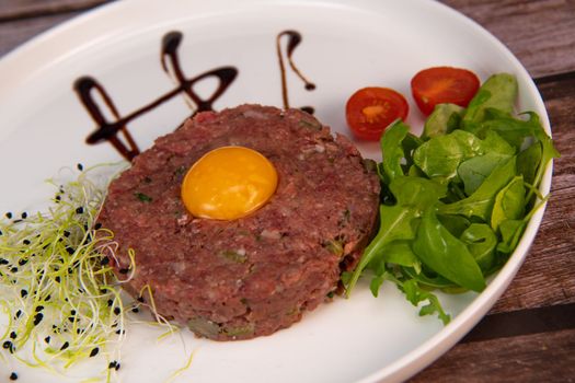 Steak Tartare with vegetables salad and french fries on dish