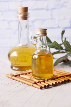 bottle of olive oil and olive leaves on yellow 