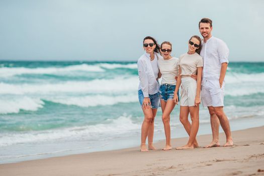 Family of four smiling and enjoy time together on the beach vacation