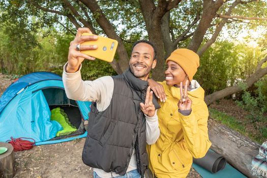 Selfie portrait couple camping - Happy black couple with yellow phone in nature having fun together.