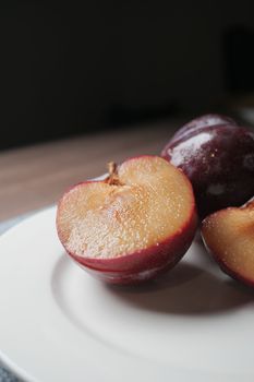 sliced fresh red plum fruit on a wooden table