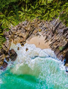 Drone aerial view at Freedom beach in Phuket Thailand, men laying down on beach in bay